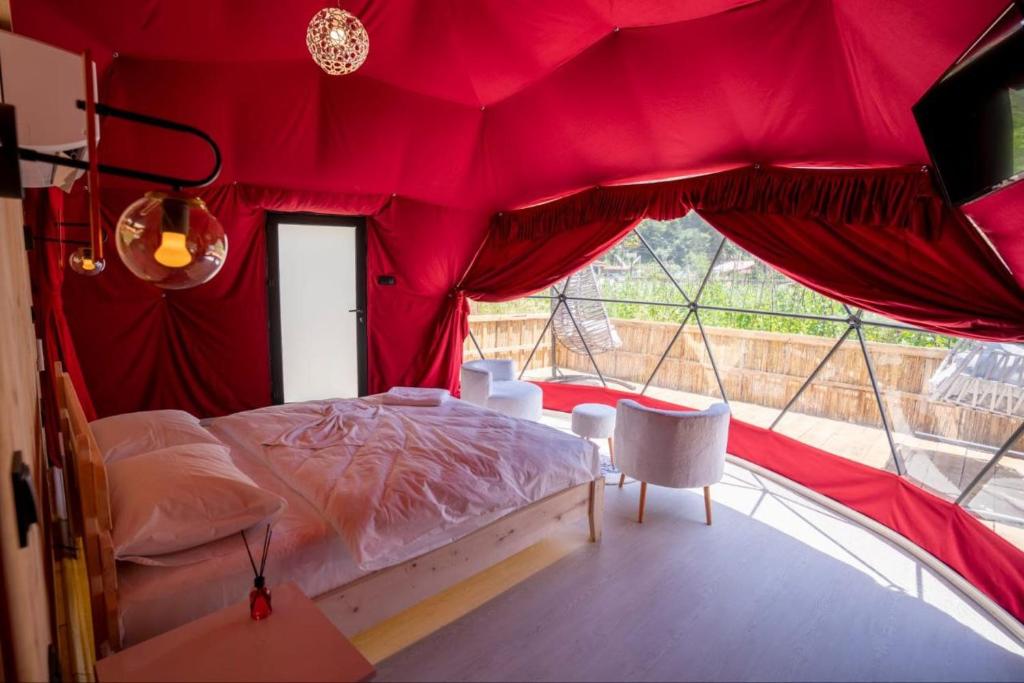 een slaapkamer met een bed in een rode tent bij Besega Bungalow in Uzungol