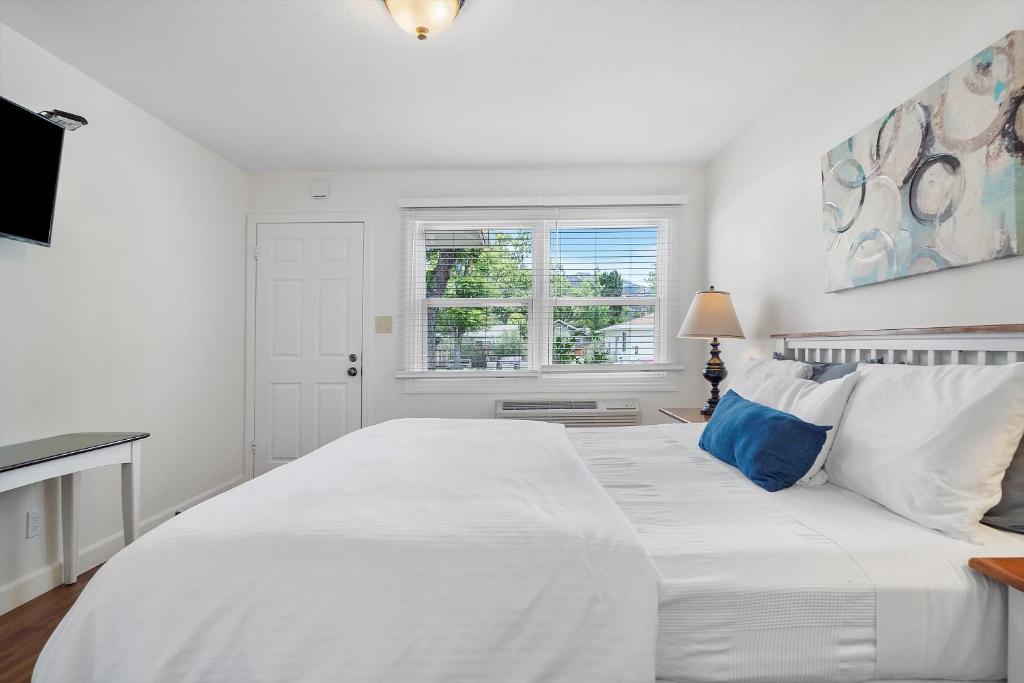 a white bedroom with a large white bed with blue pillows at Carlin's Cottage Court in Calistoga