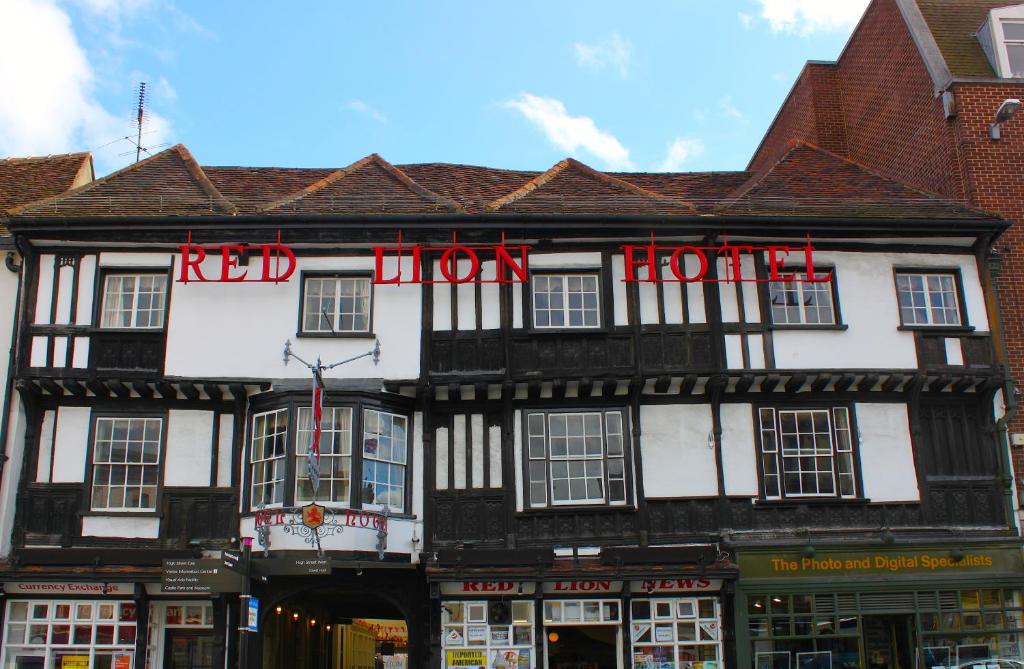 a black and white building with a red hotel sign on it at Brook Red Lion Hotel in Colchester
