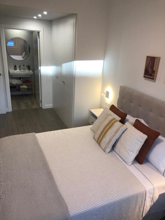 a bedroom with a large white bed with a mirror at Habitación con baño privado Bilbao in Bilbao