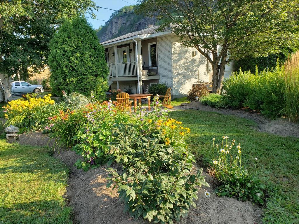 Petit-Saguenay的住宿－Résidence Touristique Les Bouleaux，庭院里带花卉的花园的房子