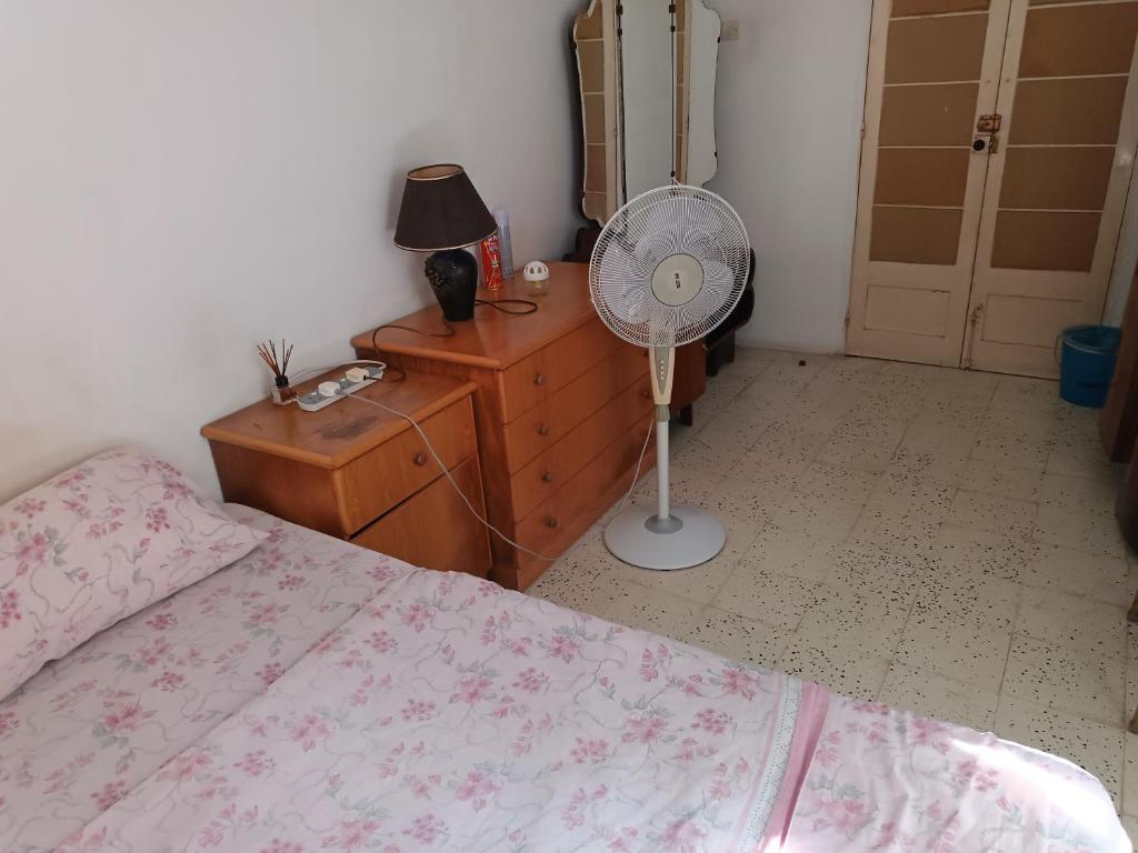 a bedroom with a bed and a dresser and a fan at House of character that Quest will like . in Ħal Balzan