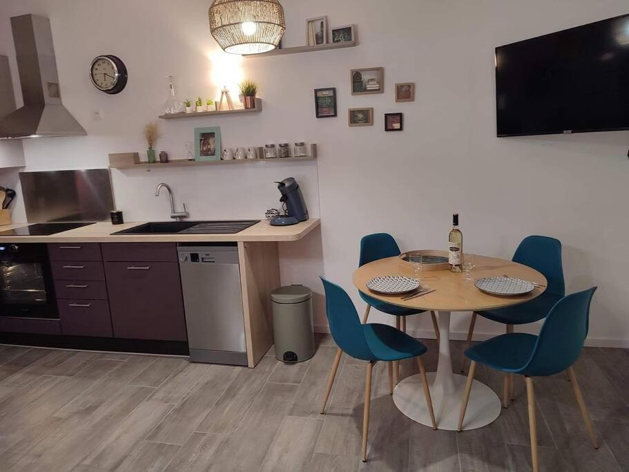 uma cozinha com uma mesa e cadeiras e um lavatório em Appartement cosy au pied des Halles,Le Rossini em Narbonne