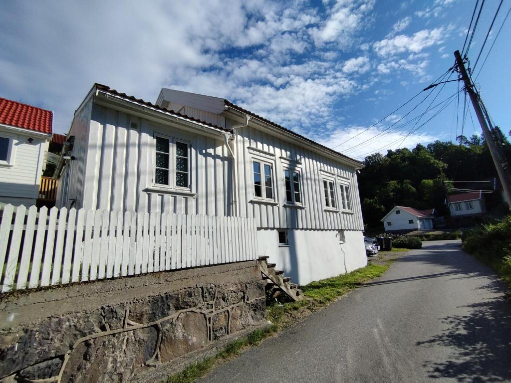 una casa bianca con una recinzione accanto a una strada di Sørlandshus med 3 soverom ad Arendal