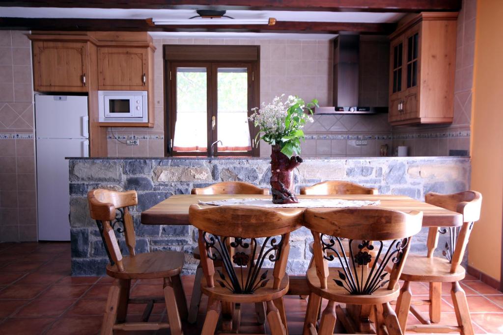 una cocina con una mesa de madera con sillas y flores. en Apartamentos Miguelo, C.B, en Saravillo