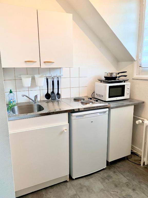 a kitchen with white cabinets and a microwave at Studio tout confort dans Boulogne in Boulogne-sur-Mer