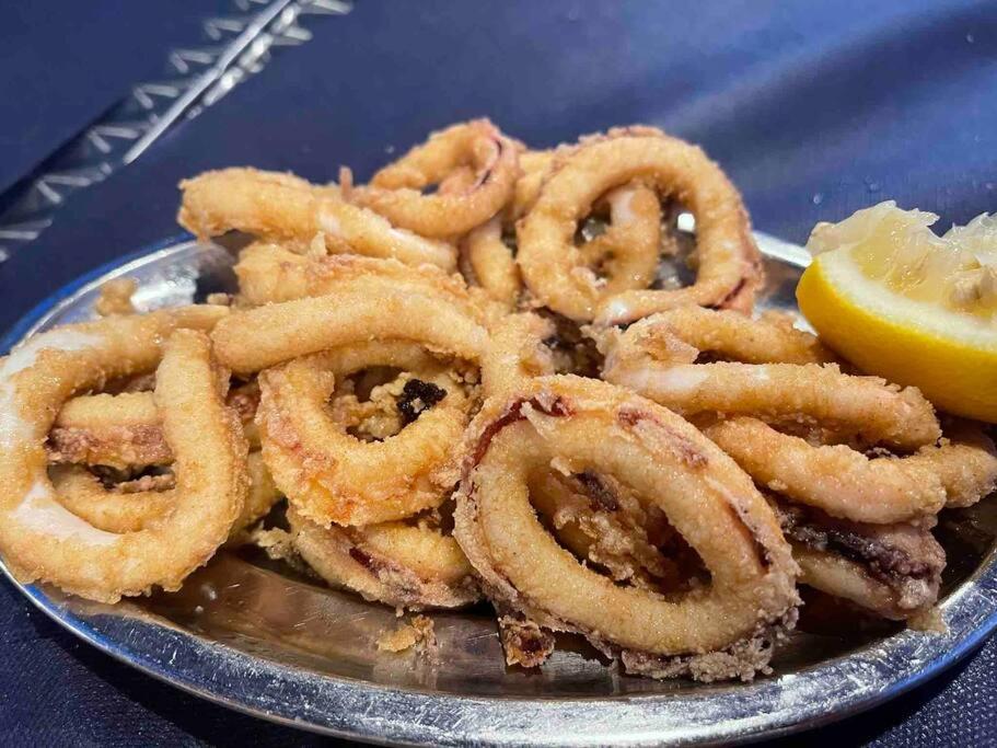 a pile of onion rings on a plate with a lemon at Origen Santoña, apartamento céntrico hasta 4 plazas y fácil aparcar, opcional garaje in Santoña