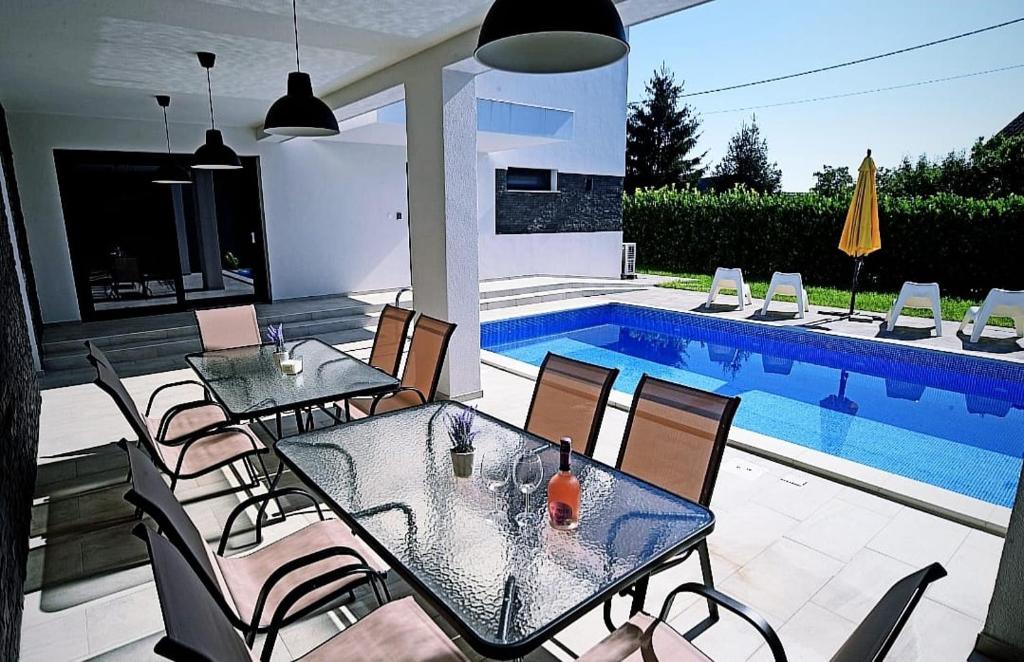 um pátio com mesas e cadeiras ao lado de uma piscina em Kuća za odmor Deda Pepo em Mičevec