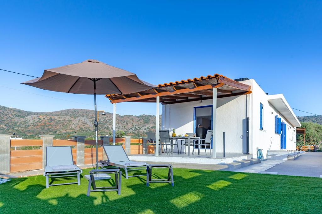 a house with a patio with chairs and an umbrella at Blue Breeze in Milatos