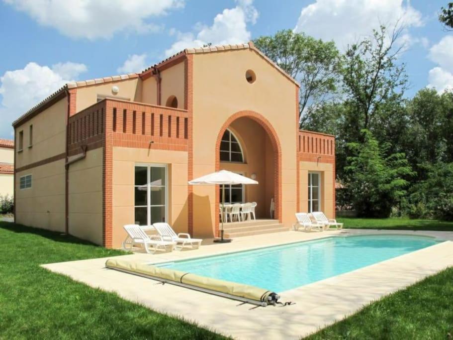 a villa with a swimming pool in front of a house at Villas du Golf Domaine Royal Green in Pont-de-Larn