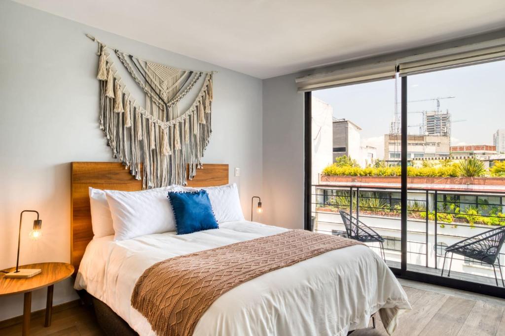 a bedroom with a bed and a large window at Chic PH Haven with rooftop, Condesa 2BR By Tasman in Mexico City