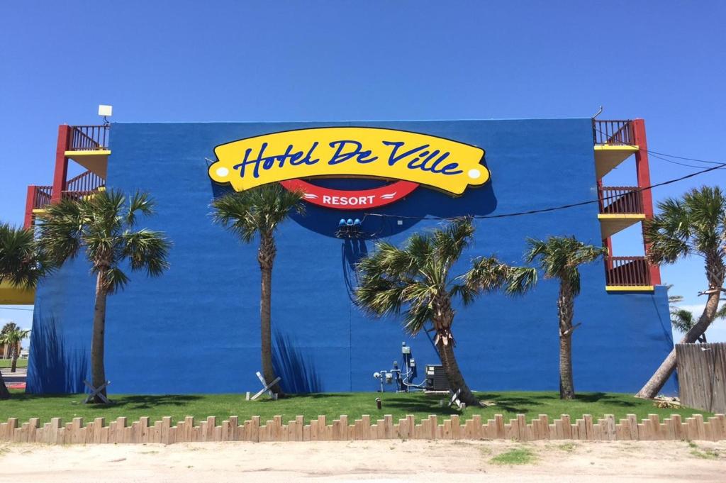 a sign on the side of a building with palm trees at Hotel DeVille in Corpus Christi
