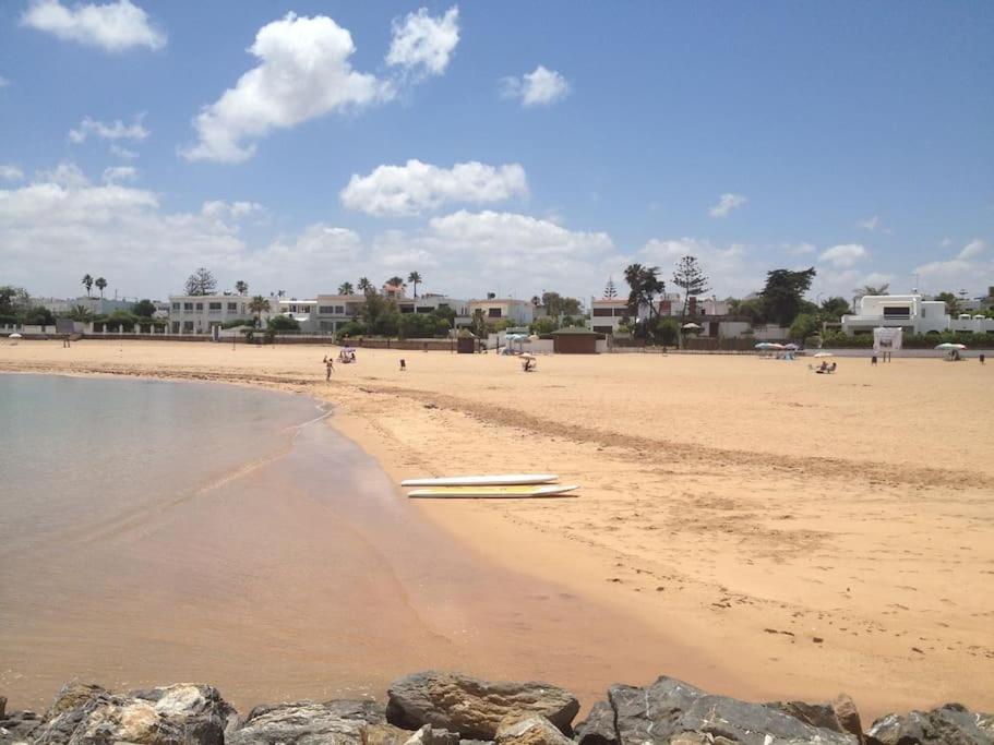 una playa de arena con unas pocas personas y edificios en Studio en face de la plage, en Temara