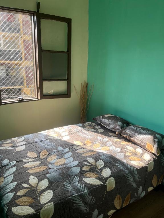 ein Schlafzimmer mit einem Bett mit einer Decke und einem Fenster in der Unterkunft Hostal Colors Bellavista in Santiago
