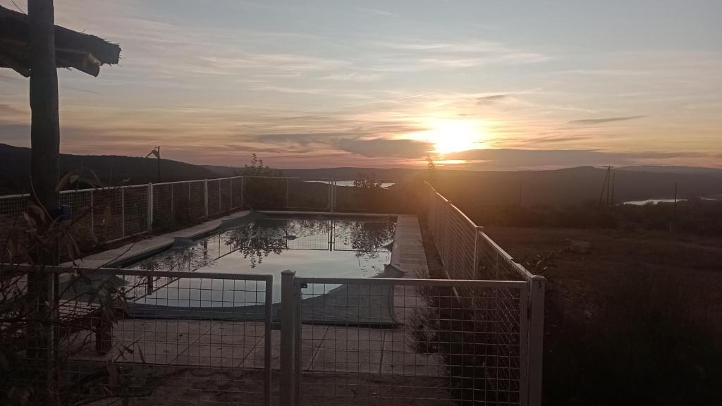 una puesta de sol sobre una piscina con el sol en el cielo en CABAÑA deMONTAÑA SANTA RITA LAS RABONAS en Las Rabonas