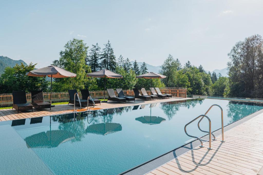 een groot zwembad met stoelen en parasols bij Wellness Aparthotel "Lechlife" incl Infinity Pool - 400m zum Lift in Reutte