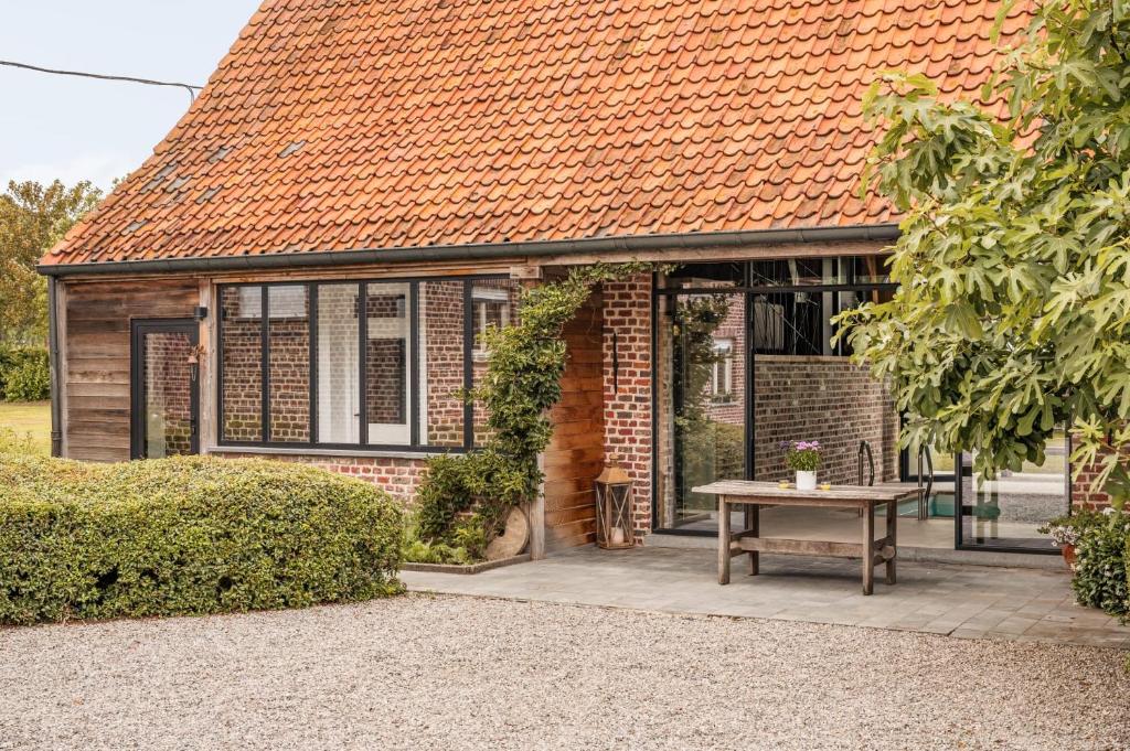 a brick house with an orange roof and a table at Hoeve-C in Ieper