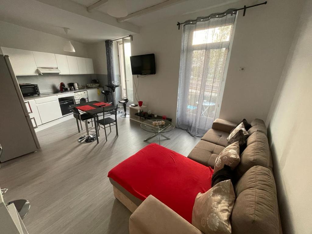 Bel appartement pour vos séjours sur la côte في نيس: غرفة معيشة مع أريكة وطاولة ومطبخ