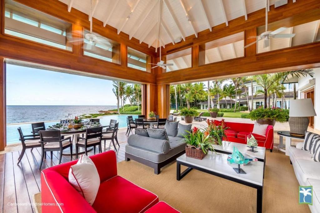an open living room with red furniture and the ocean at Sunny Vacation Villa No 37 in San Rafael del Yuma