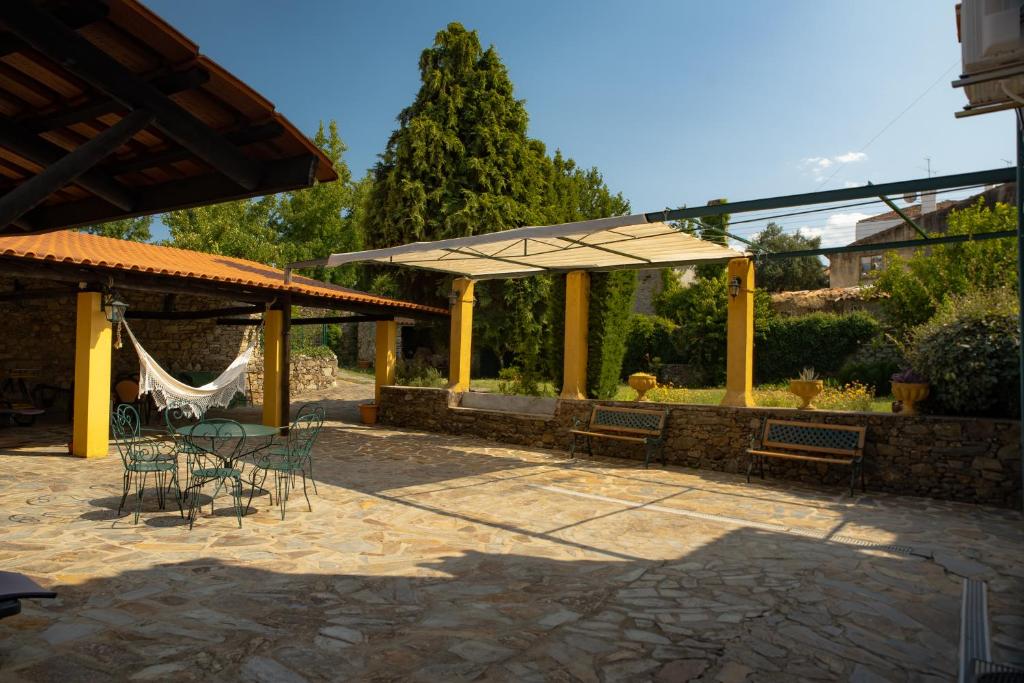 a patio with a hammock and tables and chairs at A Sobreirinha Jacuzzi e Pet Friendly in Sobreira Formosa