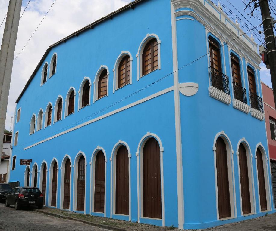 a blue building with arched windows on a street at Conforto e bom gosto no Recôncavo da Bahia. in São Félix
