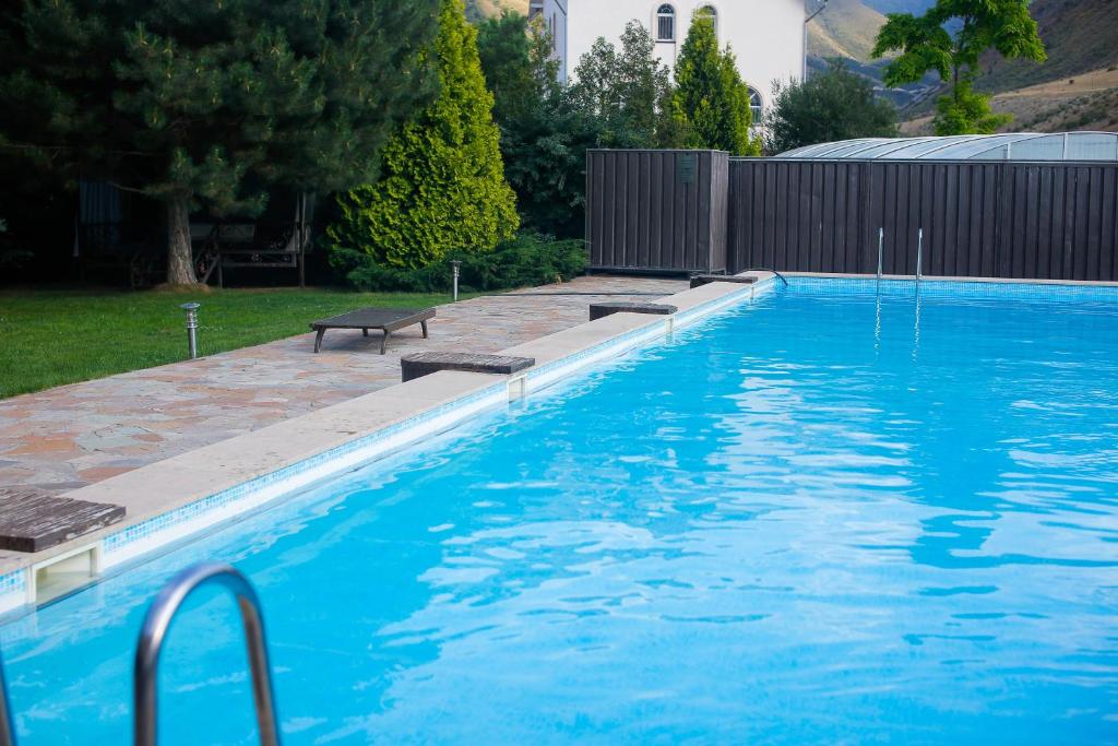 una piscina azul con un banco en un patio en Mountain View Lodge, en Alamedin