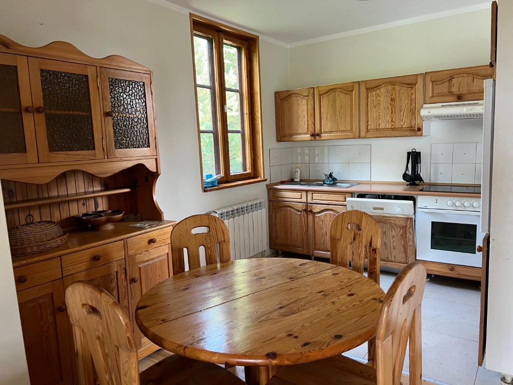 una cocina con armarios de madera y una mesa y sillas de madera. en Domki Carmen en Wierzchownia