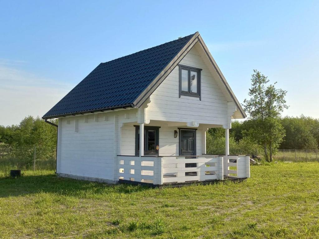 a small white house with a black roof in a field at Domek Arkadia in Gąski