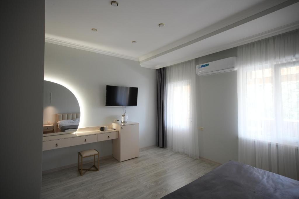 um quarto com uma cama, uma televisão e uma cadeira em WHITE HOTEL GYUMRI em Guiumri