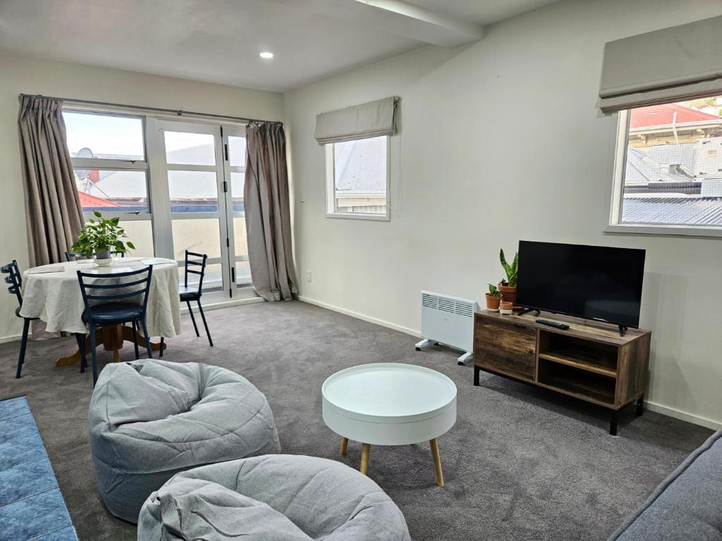 a living room with a table and a tv at 4 Bedrooms, VERY Central Townhouse! in Wellington