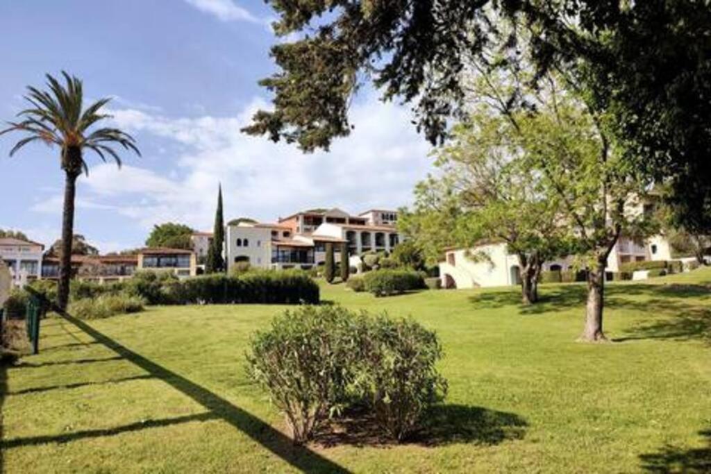 un parc avec un palmier et quelques maisons dans l'établissement Chez Adriana Appartement Cosy avec Jardin, proche plage, à Grimaud