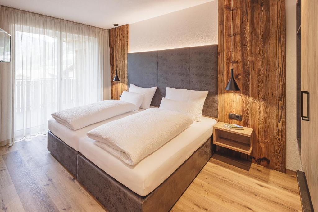 een slaapkamer met een groot bed met witte lakens bij Apartments Silva Mountain in San Giovanni in Val Aurina