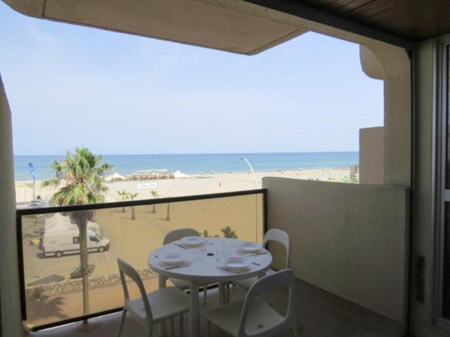 a table and chairs on a balcony with a view of the beach at Appartement face Mer, idéal famille 6NOUM12 sea view 2 bedrooms apartment in Canet-en-Roussillon
