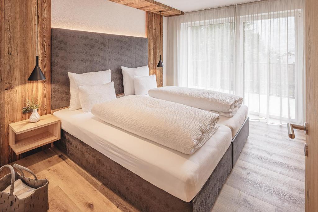 a bedroom with two beds and a large window at Apartments Silva Forest in San Giovanni in Val Aurina