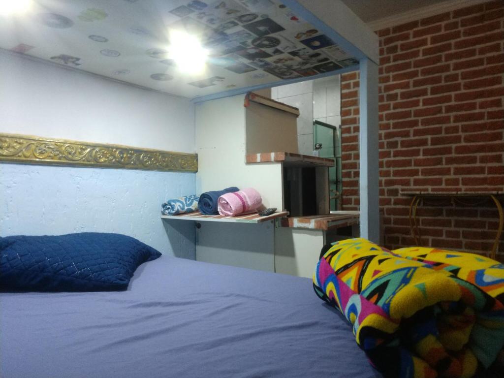 1 dormitorio con cama y pared de ladrillo en Suíte Garden en Praia Grande
