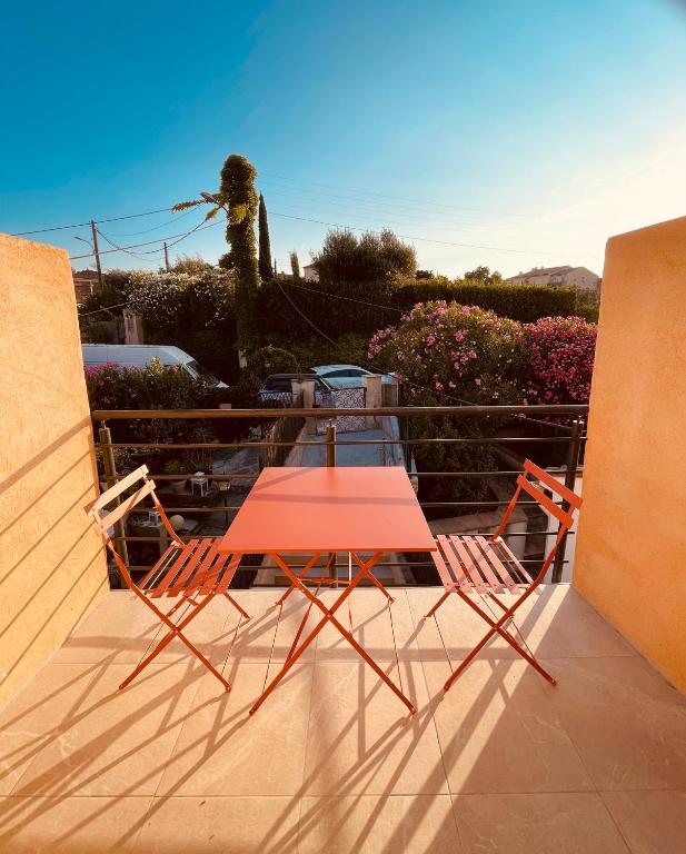 d'une table rouge et de deux chaises sur un balcon. dans l'établissement Notre cocon sudiste, à Cogolin