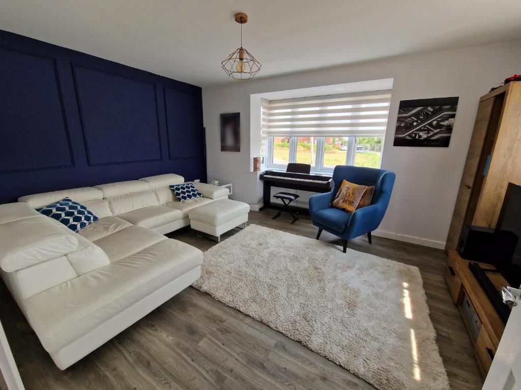 a living room with a white couch and a blue chair at Spacious 3 bedroom family home in Shinfield