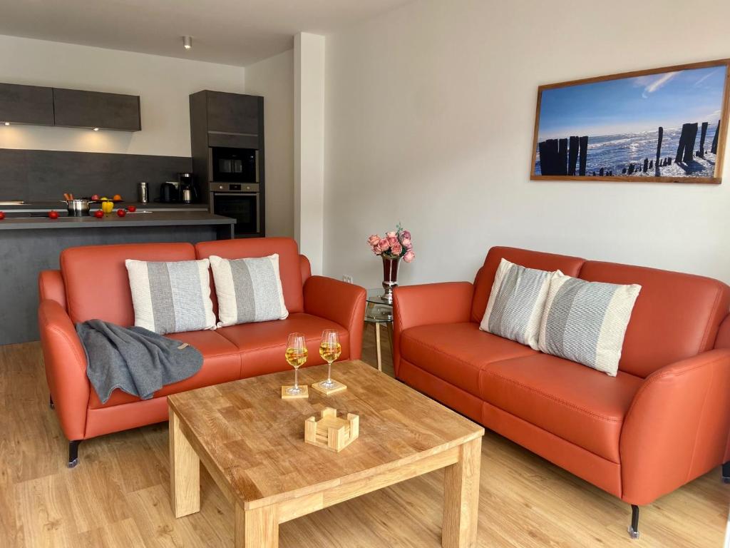 uma sala de estar com dois sofás laranja e uma mesa de centro em 2915 Wohnung 5 em Dahme