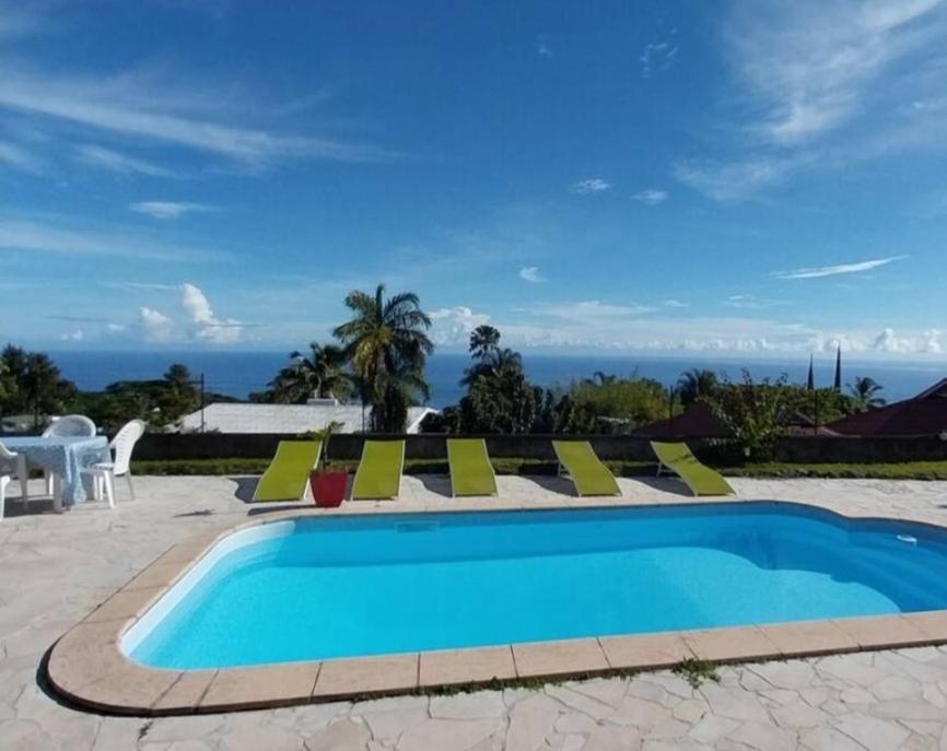 una piscina con sillas y vistas al océano en Pacific Lodge, en Mahina