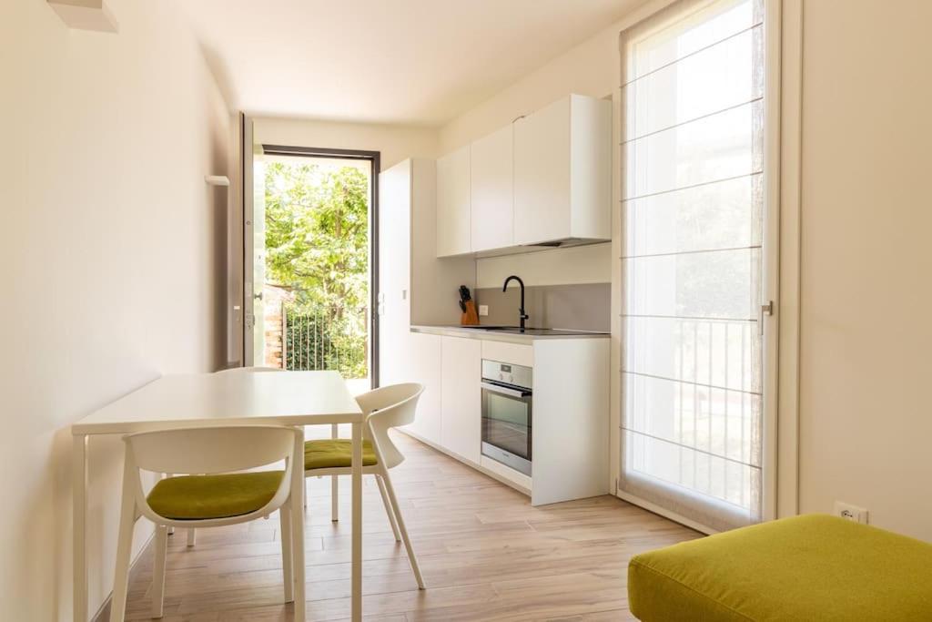una cocina con mesa y sillas blancas en Casa piccola, en Cison di Valmarino