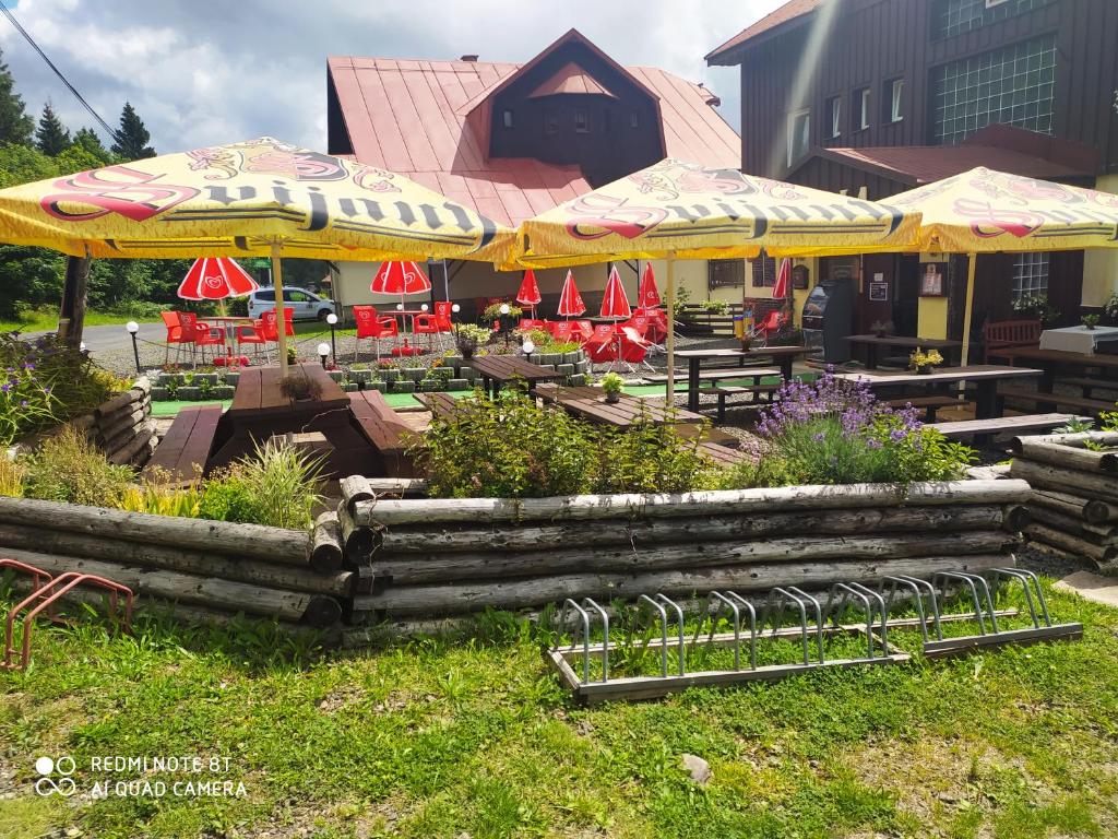 a patio with tables and chairs and umbrellas at WELLNESS Penzion Triola in Kořenov