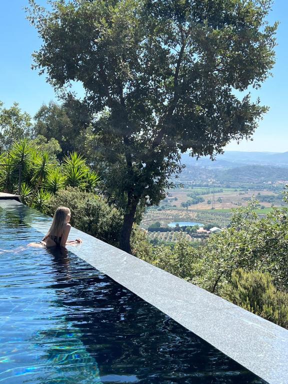 uma mulher sentada na beira de uma piscina em TheVagar Countryhouse em Belmonte