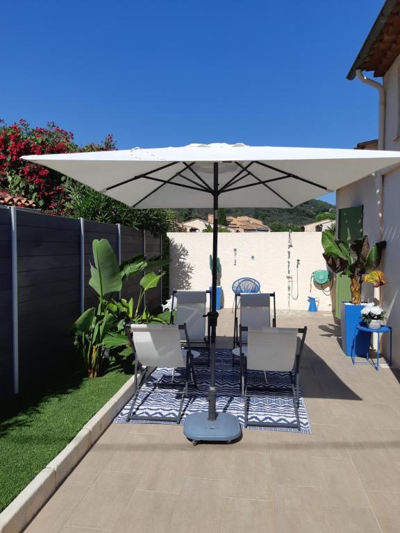 une terrasse avec une table et des chaises sous un parasol dans l'établissement Villa 4 personnes piscine, à Pégomas