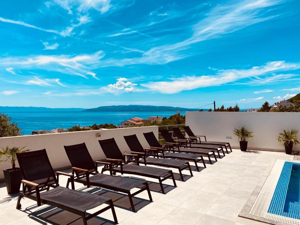 eine Sitzreihe auf einer Terrasse mit einem Pool in der Unterkunft Holiday Home Meri in Makarska