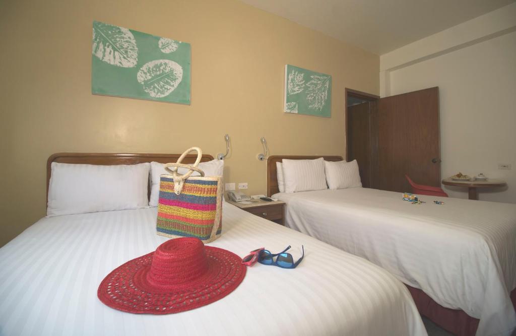 a red hat sitting on top of two beds at Olmeca Plaza Urban Express in Villahermosa