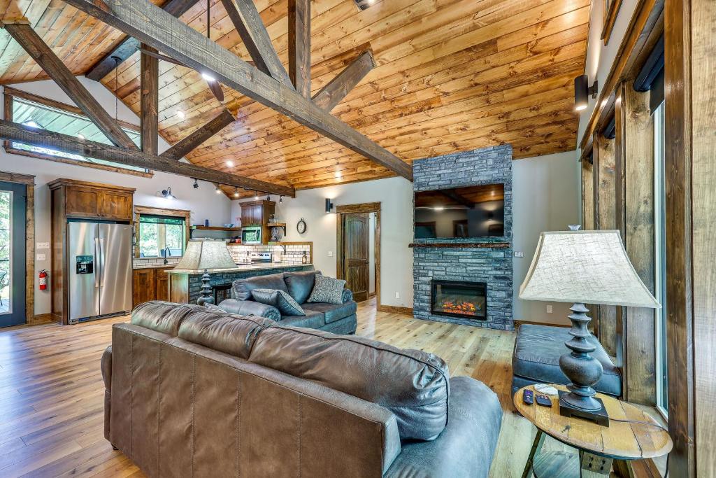 a living room with a leather couch and a fireplace at Big Cedar Vacation Rental with Deck and Hot Tub! in Hodgen