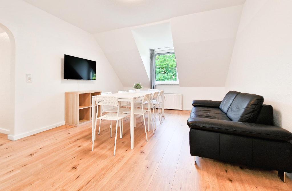 a living room with a table and a black leather couch at RAJ Living - 3 and 4 Room Apartments in Duisburg