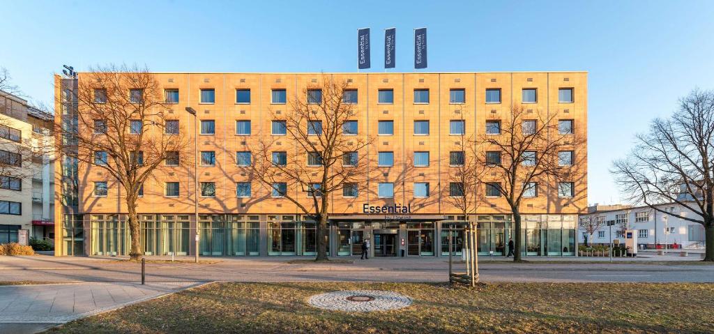 a large brick building with trees in front of it at Essential by Dorint Berlin-Adlershof in Berlin