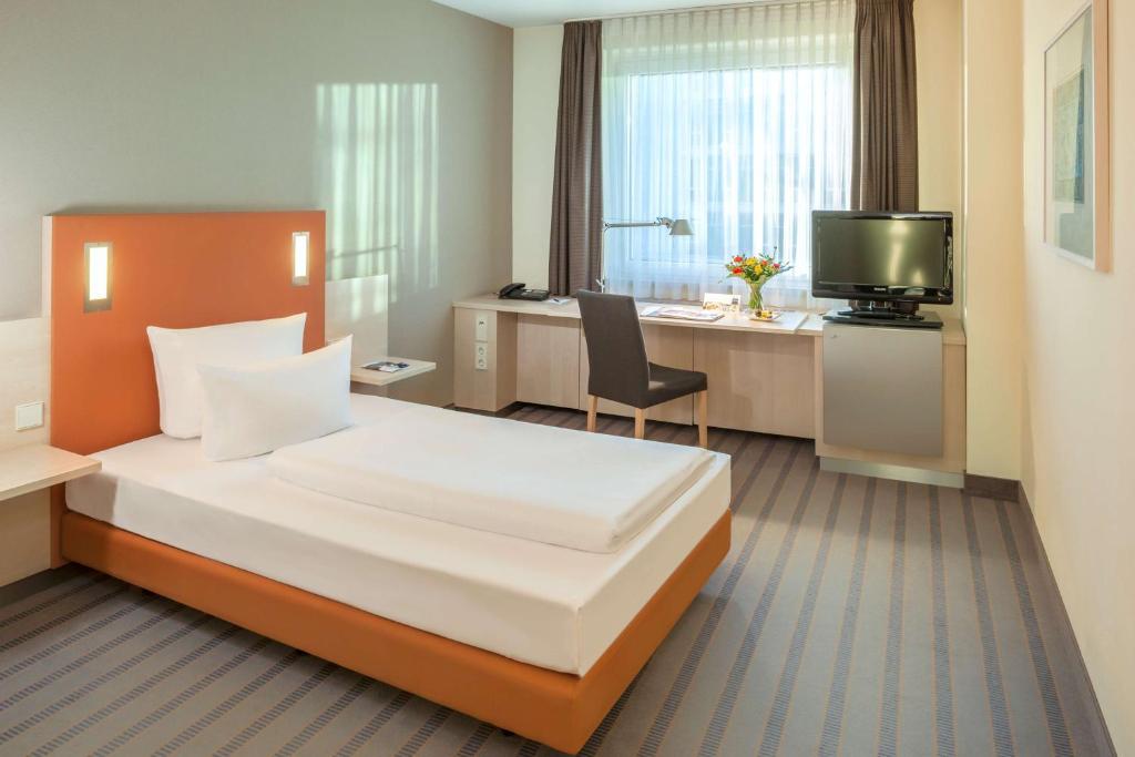 ベルリンにあるEssential by Dorint Berlin-Adlershofのベッドとデスクが備わるホテルルームです。