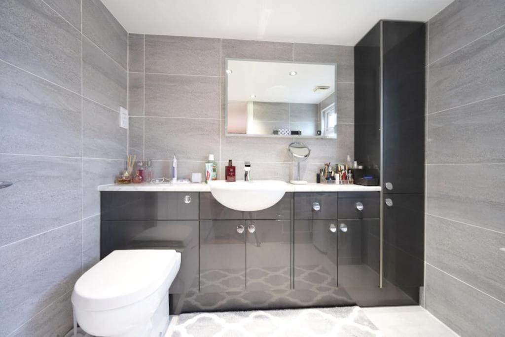 a bathroom with a white toilet and a sink at Spacious 4-Bed Family House in Portsmouth